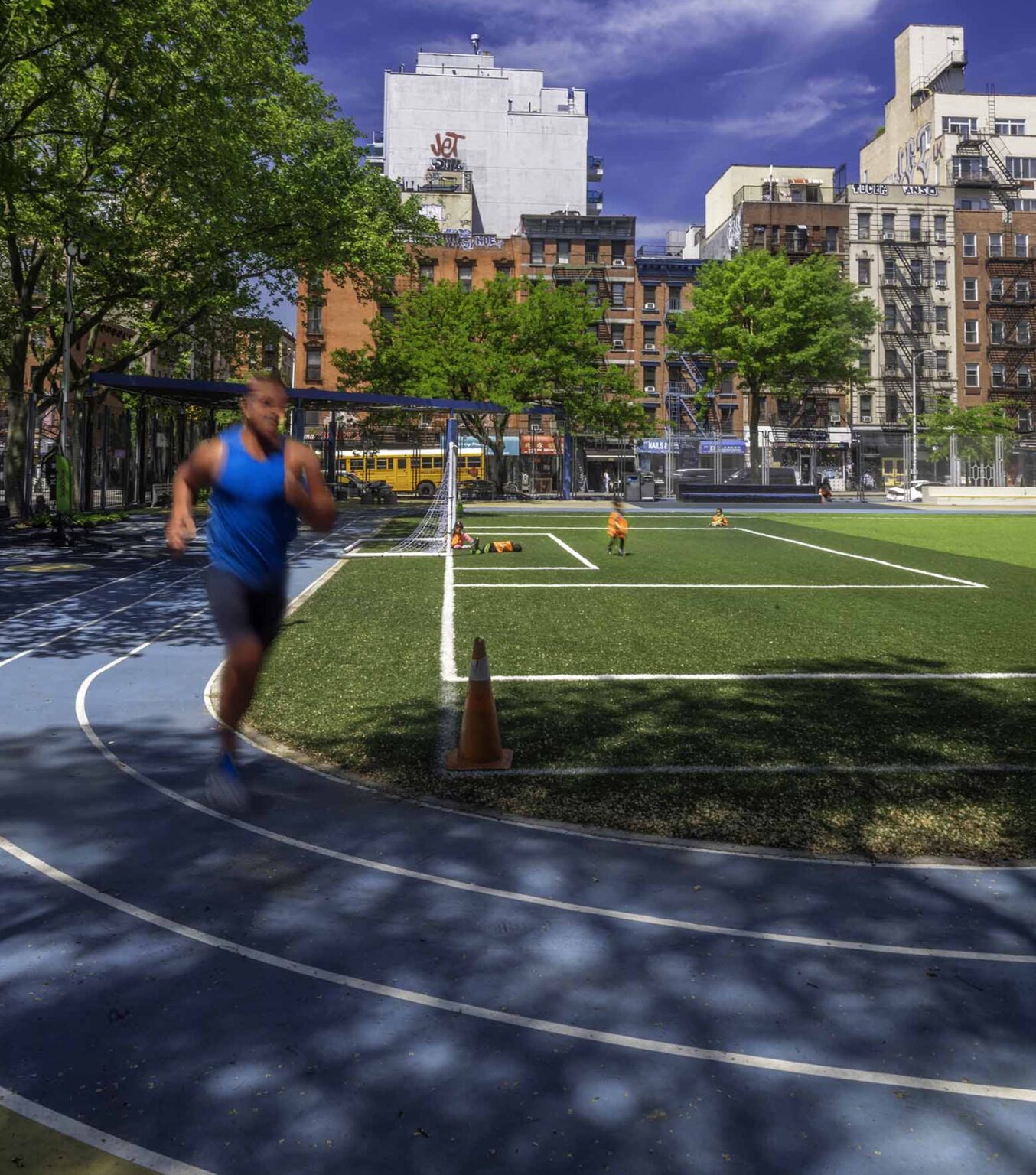 Man running on track around athletic field.
